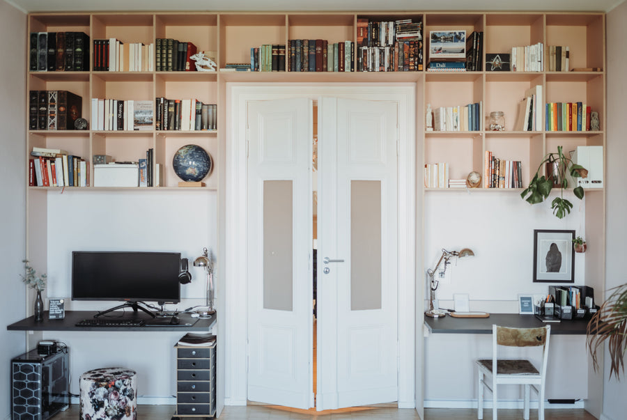 Altbau-Durchgangszimmer mit Flügeltür, umlaufendem Einbauregal und zwei Arbeitsplätzen links und rechts der Tür