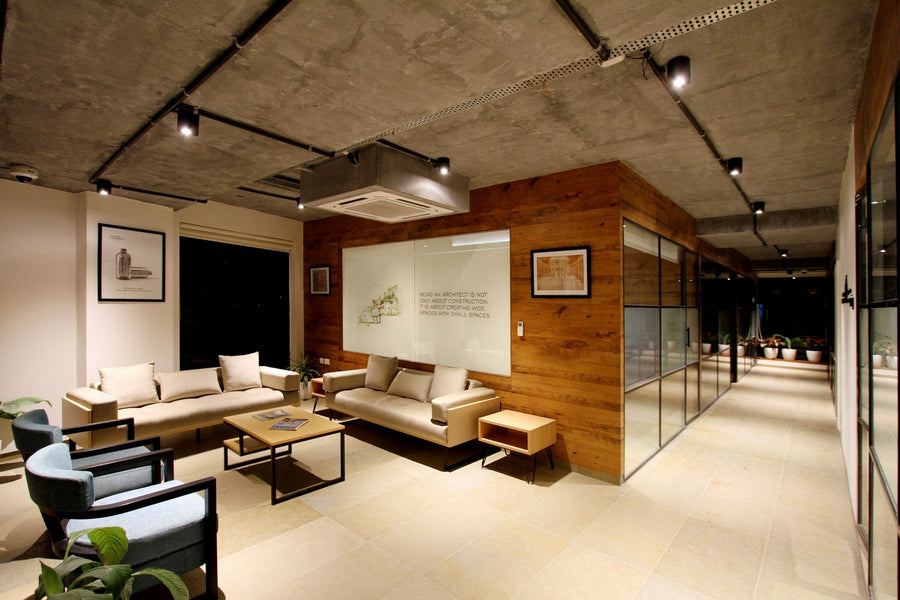 Hochwertig ausgestattete Büro-Lounge mit Sofas, Sesseln, Holzwand und Glastrennwänden