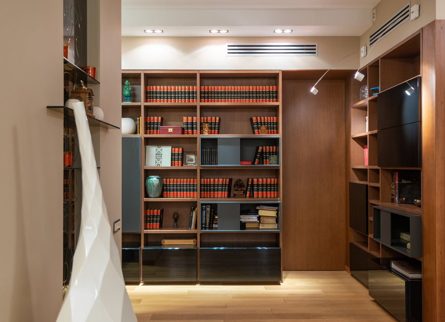 Kanzleibüro mit raumhohem Bücherregal aus dunklem Holz, gebundenen Fachbüchern und warmer Beleuchtung – seriös eingerichtet